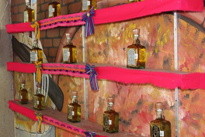 Bottles of liquor on a colorful decorated shelf with red cloth and bows.