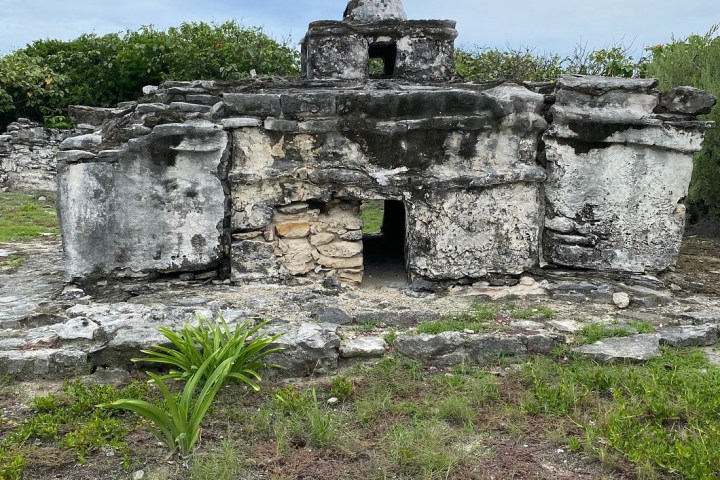 Ancient stone ruin with grassy foreground and cloudy sky in the background.